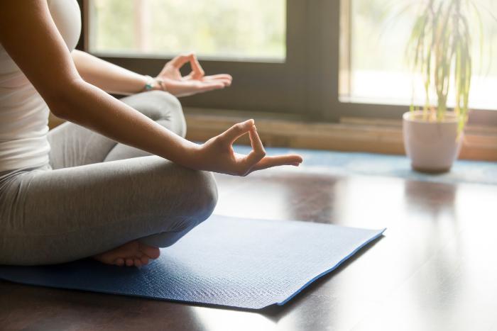 Frau praktiziert Metta Meditation auf der Yogamatte