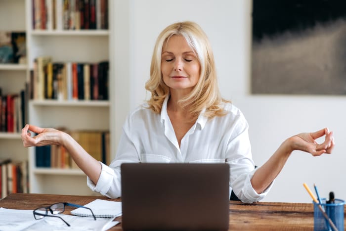 Frau praktiziert Metta Meditation vor dem Laptop